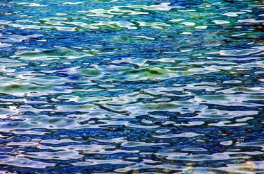 Traunsee Gölü 'nün kıyı bölgesindeki sularının arka planı. Suyun altındaki taşların renkli dokusu.