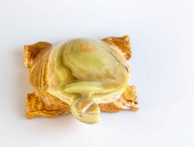 Beyaz arka planda taş bir kaplumbağa figürü. Doğal taştan yapılmış, yakın plan..