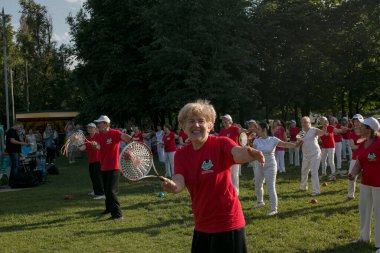 Dnepr, Ukrayna - 06.21.2021: Parkta tenis topu ve raketle sağlık ve spor yapan bir grup yaşlı insan.