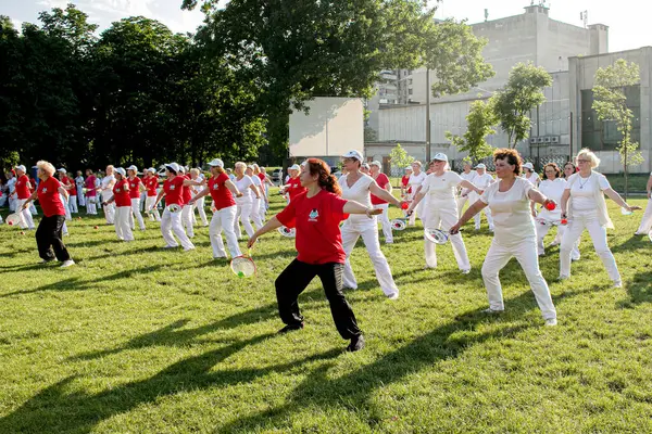 Dnepr, Ukrayna - 06.21.2021: Parkta tenis topu ve raketle sağlık ve spor yapan bir grup yaşlı insan.
