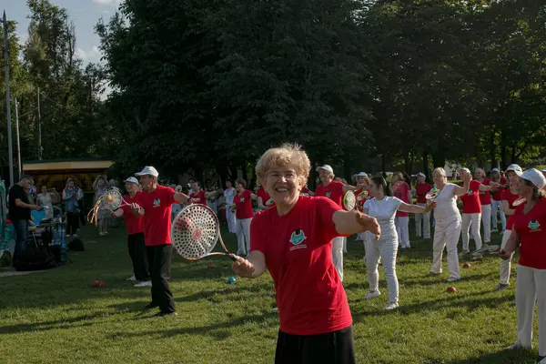 Dnepr, Ukrayna - 06.21.2021: Parkta tenis topu ve raketle sağlık ve spor yapan bir grup yaşlı insan.