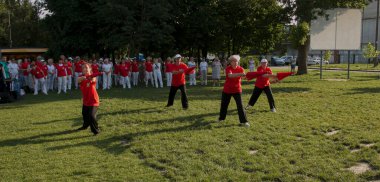 Dnepr, Ukrayna - 06.21.2021: Parkta şemsiyelerle sağlık ve spor yapan bir grup yaşlı insan.