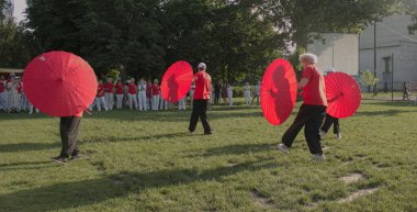 Dnepr, Ukrayna - 06.21.2021: Parkta şemsiyelerle sağlık ve spor yapan bir grup yaşlı insan.