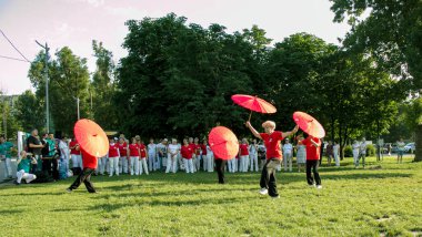 Dnepr, Ukrayna - 06.21.2021: Parkta şemsiyelerle sağlık ve spor yapan bir grup yaşlı insan.