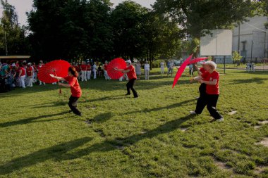 Dnepr, Ukrayna - 06.21.2021: Parkta şemsiyelerle sağlık ve spor yapan bir grup yaşlı insan.