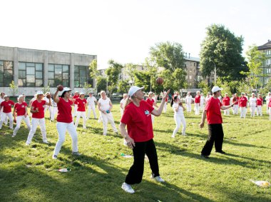 Dnepr, Ukrayna - 06.21.2021: Parkta bir topla sağlık ve spor yapan bir grup yaşlı insan.