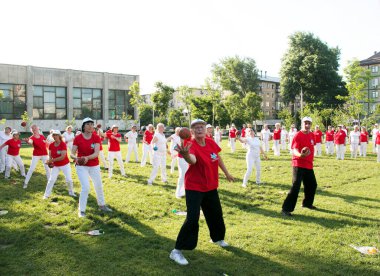 Dnepr, Ukrayna - 06.21.2021: Parkta bir topla sağlık ve spor yapan bir grup yaşlı insan.