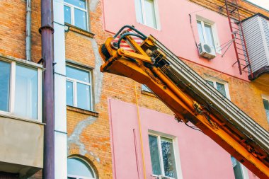 Eski tuğladan bir apartmanın arka planına karşı bir vinç..