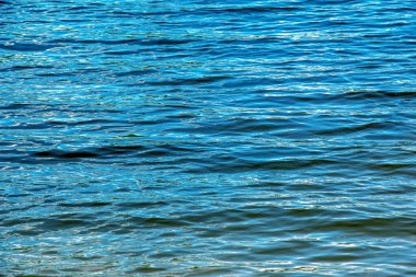 Water ripple texture background. Wavy water surface during sunset, golden light reflecting in the water.