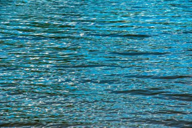 Water ripple texture background. Wavy water surface during sunset, golden light reflecting in the water.