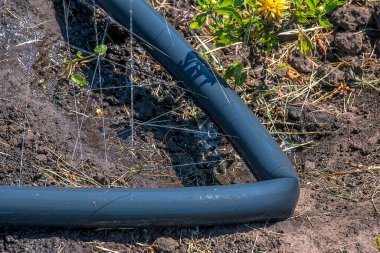 En basit sulama sistemi. Topraktaki delikli hortum su basıncının altında yatıyor..