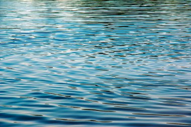 Water ripple texture background. Wavy water surface during sunset, golden light reflecting in the water.