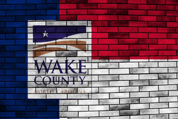 stock image Flag of the city of Wake County, North Carolina, USA, on a background of the stone wall. Conceptual collage.