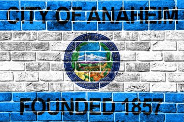 Flag of the city of Anaheim, California, USA, on a background of a brick wall. Conceptual collage. clipart