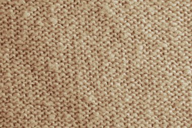 Bej örülmüş halıyı yakından gösteren gerçekçi bir tasvir. Bej arka planda tekstil dokusu. Ayrıntılı sıcak iplik arka planı. Doğal yün kumaş, süveter parçası..