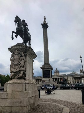 London, UK - 06.05.2019: Statue of King Charles I in Trafalgar Square in London and the silhouette of Nelsen's Column in the background. clipart