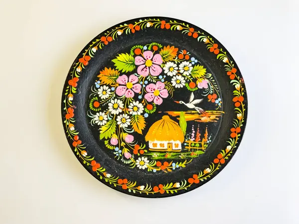 Dnepr, Ukrayna - 01.23.2025: Beyaz zemin üzerinde siyah ahşap Petrykivka tabağı. Ahşap üzerinde sanatsal bir tablo..