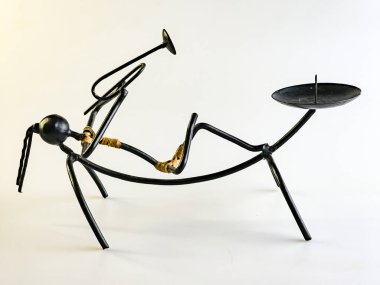 Beyaz arka planda trompet çalan kadın şeklinde siyah kablodan yapılmış bir şamdan..