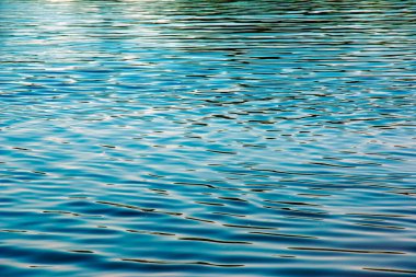 Water ripple texture background. Wavy water surface during sunset, golden light reflecting in the water.