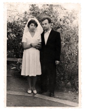 Novoshakhtinsk, SSCB - 1975: Çiçek açan bir bahçede gelin ve damadın klasik portresi. SSCB 'de çekilmiş eski bir retro fotoğraf..