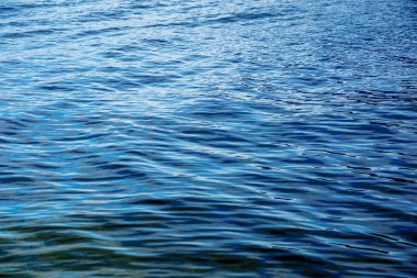 Alplerdeki Traunsee Gölü 'nün su arka planı. Berrak bir dağ gölünün yansımalarının renkli dokusu.