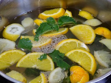 Ev yapımı limonata. Portakal, limon ve nane parçalarını kaynak suyuyla dolu büyük bir kapta..