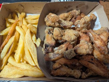 Geleneksel ekmek arası tavuk budu ve patates kızartması karton teslimat kutusunda..