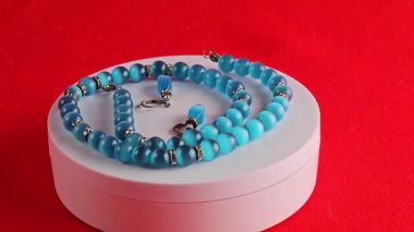 Kolyeye yakın çekim ve mavi kedi gözü efektli küpeler. Beyaz arka plan. Zirkon ekler.