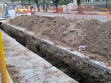 Cordoba, Argentina - May 08, 2025: Construction work. Laying underground utilities in city center. Trench and soil dumps for the laying utilities.