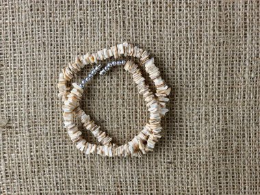 Bej arka plandaki bir kadına hediye olarak el yapımı cilalı bej kabuklu kolye. Doğal mücevherler. Yaz mücevherleri.