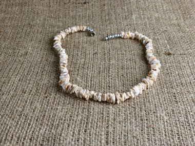 Beyaz arka plandaki bir kadına hediye olarak el yapımı, parlatılmış bej kabuklu kolye. Doğal mücevherler. Yaz mücevherleri.