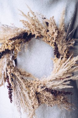 Şık bir sonbahar çelengi. Kuru otlardan, kır çiçeklerinden ve buğdaydan kırsal çelenk tutan kadın elleri. Sonbahar tatili atölyesi. Çiçekçi boho çelengi yapıyor.. 
