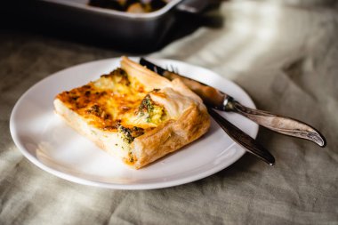 Sliced traditional french open quiche pie with cheese and broccoli on light linen background. A piece of vegetable quiche with broccoli and cheese. Vegetarian pie. High quality photo.
