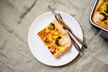 Sliced traditional french open quiche pie with cheese and broccoli on light linen background. A piece of vegetable quiche with broccoli and cheese. Vegetarian pie. Top view. High quality photo. 