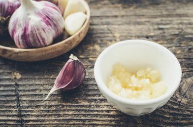 Eski ahşap arka planda kırsal tarzda sarımsak. Taze soyulmuş mor sıkılmış sarımsak..