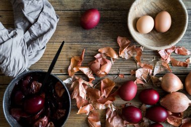 Kırsal ahşap arka planda doğal boya soğanıyla boyanmış Paskalya yumurtaları. Paskalya için doğal boya ile yumurta boyama işlemi. Gıda boyasıyla doğal ekolojik lekeler. Üst görünüm.