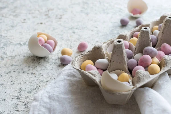 Easter composition with mini chocolate eggs in pastel colors on grey concrete background. Happy Easter Holidays. Copy space.