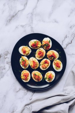 Somon ve mayonezli baharatlı yumurta dolması. Paskalya yemeği konsepti, bahar çiçekleri, paskalya tavşanı. Siyah arka planda somonlu ev yapımı baharatlı yumurta. Üst Manzara. Yüksek kalite fotoğraf.