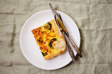 Sliced traditional french open quiche pie with cheese and broccoli on light linen background. A piece of vegetable quiche with broccoli and cheese. Vegetarian pie. Top view. High quality photo. 