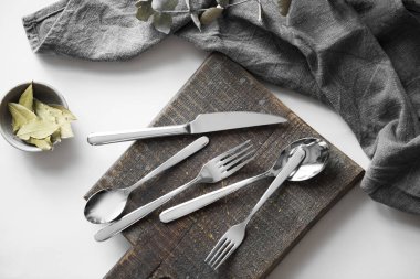 Çatal bıçak takımı - çay kaşığı, yemek kaşığı, tatlı çatalı, masa çatalı ve masa bıçağı beyaz arka planda. Güzel gümüş çatal bıçak takımı. Gri yüzeyde paslanmaz çelik çatal bıçak seti. Stüdyo ürün fotoğrafçılığı.