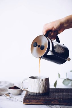 Filtre damlatıcıyla kahve yapmak. Kağıt filtreden damlayan kahve. Kahve yapmak için alternatif bir yol. Makro yakın çekim. Siyah arka planda cam çaydanlıktan beyaz fincana kahve dökülüyor..