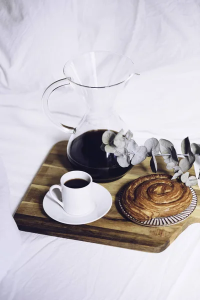 Brewing coffee with a filter dripper. Coffee dripping through a paper filter. Alternative way to make coffee. Morning breakfast in bed concept - coffee and cinnamon roll.