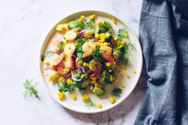 Taze sebzeli sağlıklı salata - mısır, avokado, kırmızı soğan, karides ve beyaz tabakta kişniş. Vejetaryen yemek tarifi. Diyet fitness menüsü. Düz yatıyordu. Mermer arkaplanda üst görünüm. 