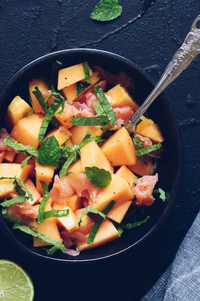 Sağlıklı salata. Somon, kavun, nane ve limon. Siyah bir kasede. Vejetaryen yemek tarifi. Diyet fitness menüsü. Üst Manzara. Düz yatıyordu.