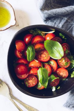 Beyaz mermer arka planda kiraz domatesli sağlıklı salata ve fesleğen. Domates salatası. Vejetaryen vejetaryen yemek tarifi. Diyet fitness menüsü. Üst Manzara. Düz yatıyordu.