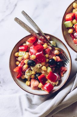 Domatesli zengin protein Yunan salatası, dolma biber, salatalık, siyah zeytin, peynir, soğan ve nohut. Sebze salatası. Vejetaryen lezzetli yemek tarifi. Bitki temelli menü. Üst görünüm.