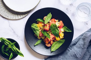 Farklı domatesli sağlıklı Caprese salatası, mozzarella, pesto sosu, çam fıstığı ve beyaz mermer arka planda fesleğen. Domates salatası. Vejetaryen lezzetli yemek tarifi. Üst görünüm.