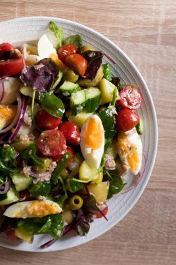Nicoise Salatası - Fransız usulü salata yumurta, ton balığı, kiraz domatesleri, yeşil zeytin, patates, yeşil fasulye ve beyaz mermer kaplama salatalık. Lezzetli yemek tarifi kitabı. Üst görünüm.