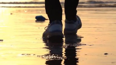 Akşam vakti sahilde yürüyen bir adam. 