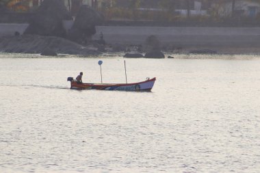 Teknede bir adam teknenin etrafında balık arıyor.